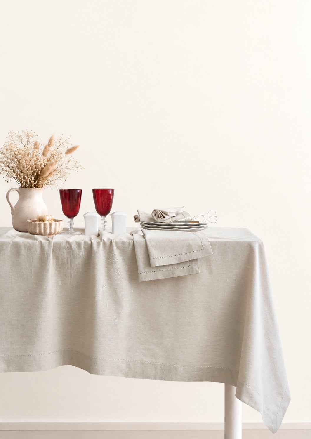 Jolly Light Beige tablecloth styled on a dining table with ceramics and glassware