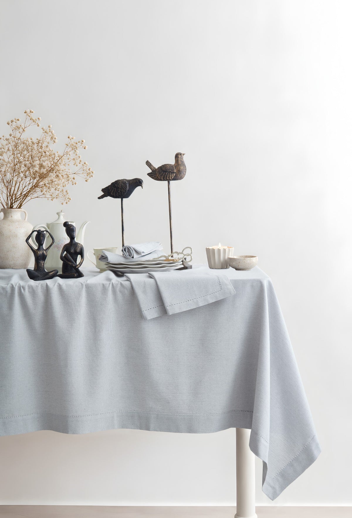 Jolly Light Grey tablecloth styled on a dining table with decorative objects