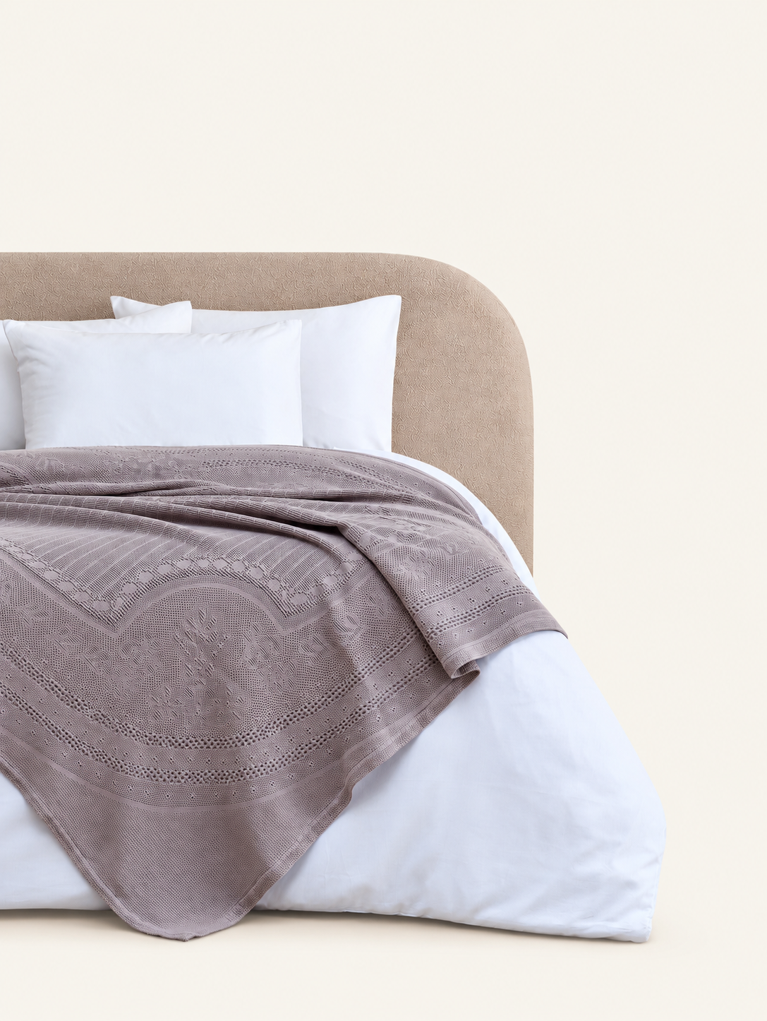 Morella Beige decorative throw displayed on a bed against a light beige background