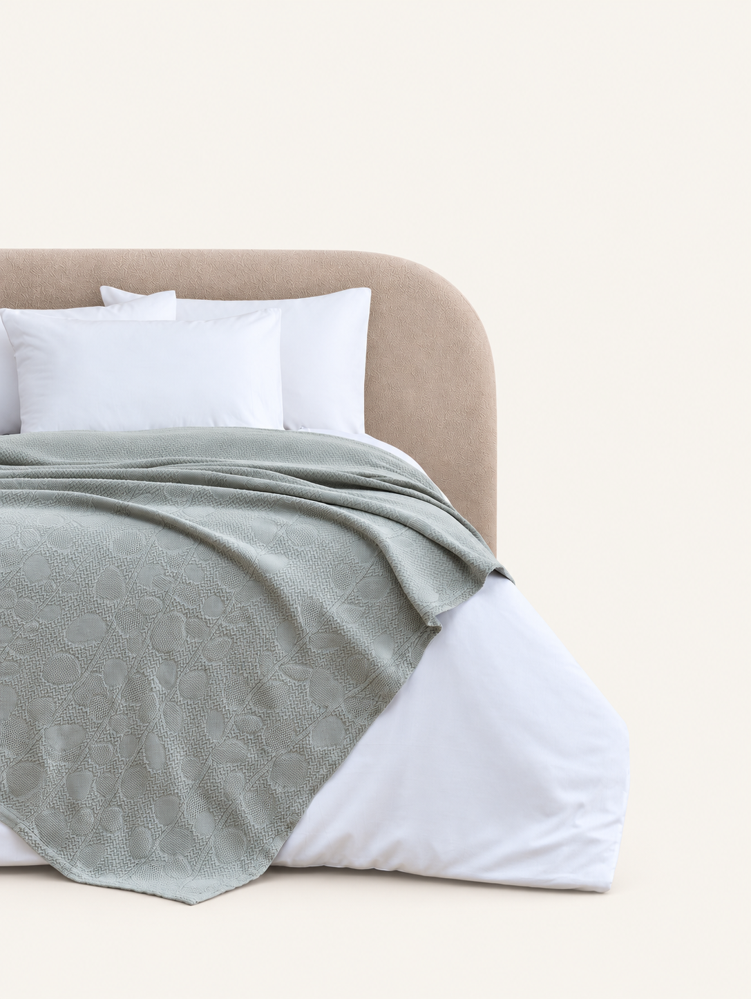 Solena khaki throw with leaf motifs displayed on a bed against a light beige background