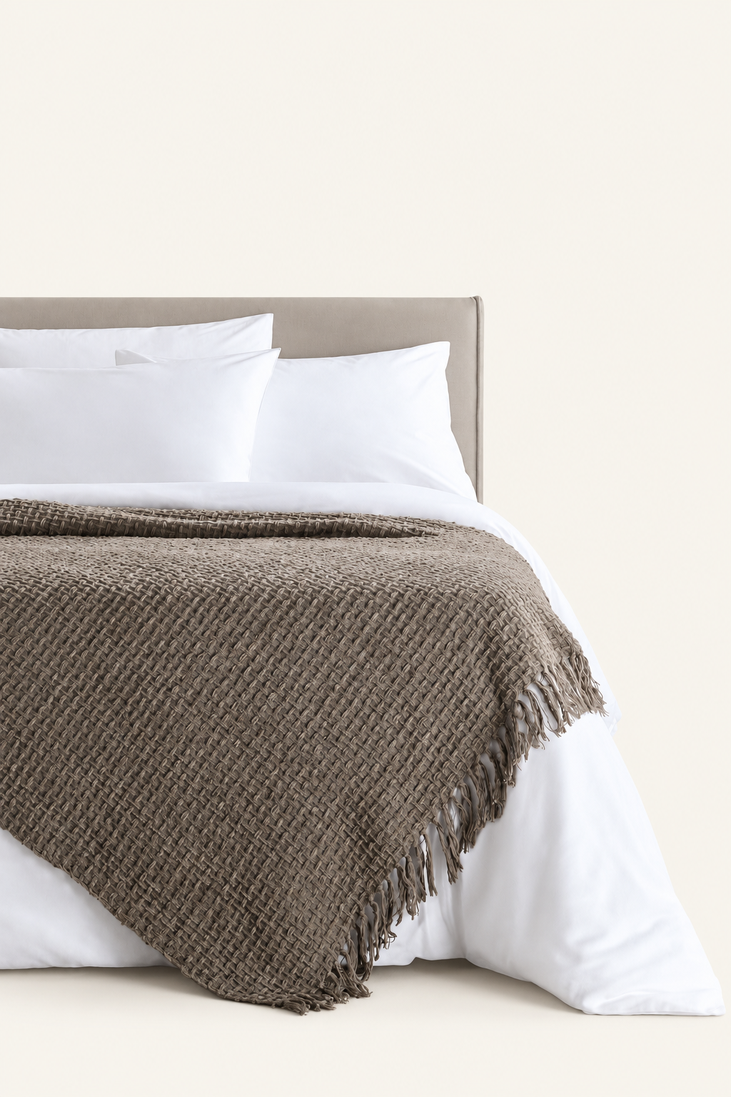Devina Grey throw — displayed on a bed against a light beige background