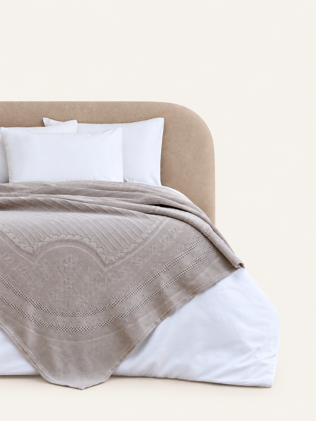 Morella Grey decorative throw displayed on a bed against a light beige background